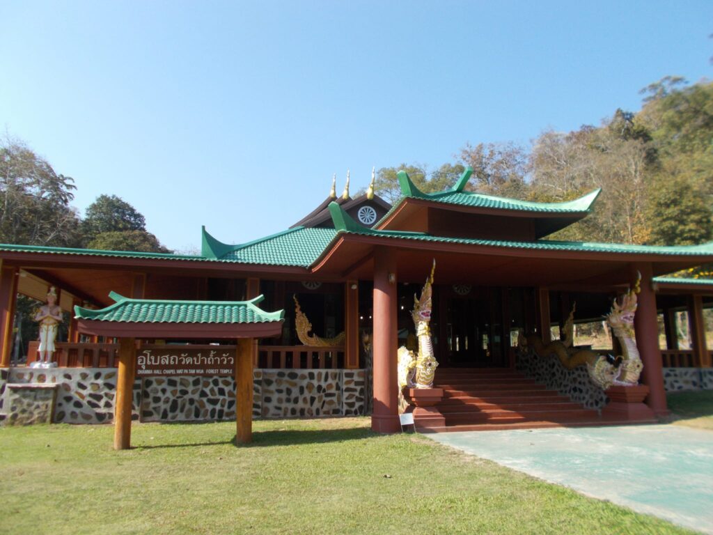 Wat Pu Tam Wua Forst Retreat Monastery, Thailand. Man sieht die Eingangshalle mit geschwungenen Dächern. 